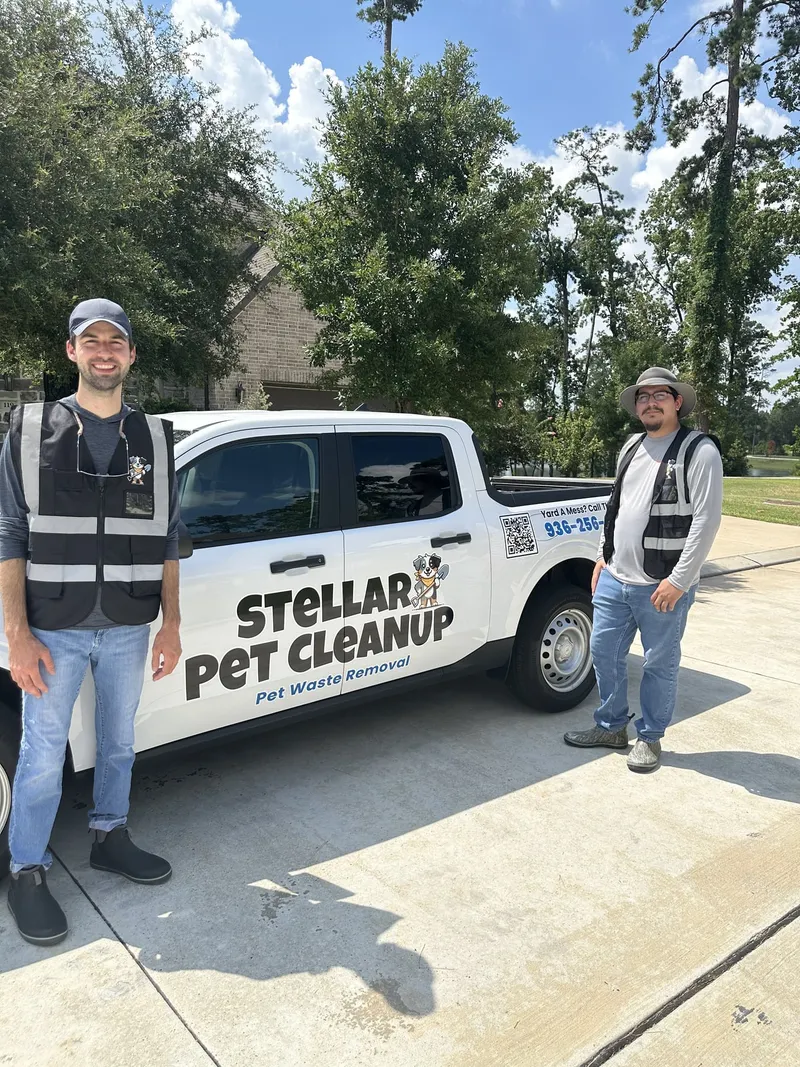 Stellar Pet Cleanup owner and a technician in safety vests standing beside the wrapped company truck in a driveway